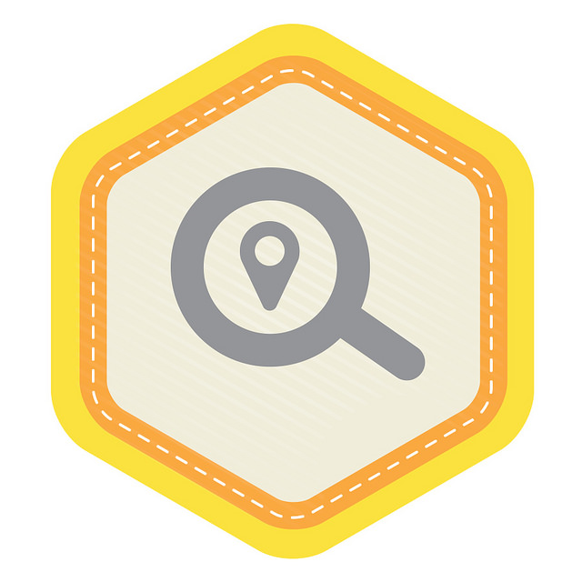A hexagonalbadge with a magnifying glass in the middle with a map pin icon inside the magnifying glass